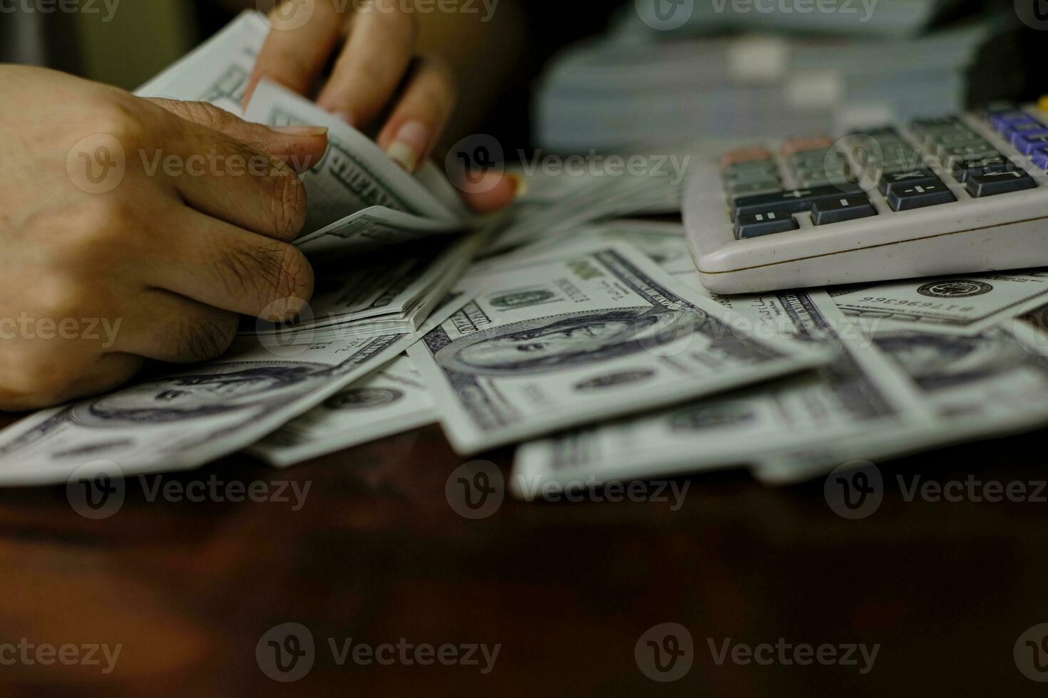 donne d'affari che contano soldi su una pila di banconote da 100 dollari USA us foto