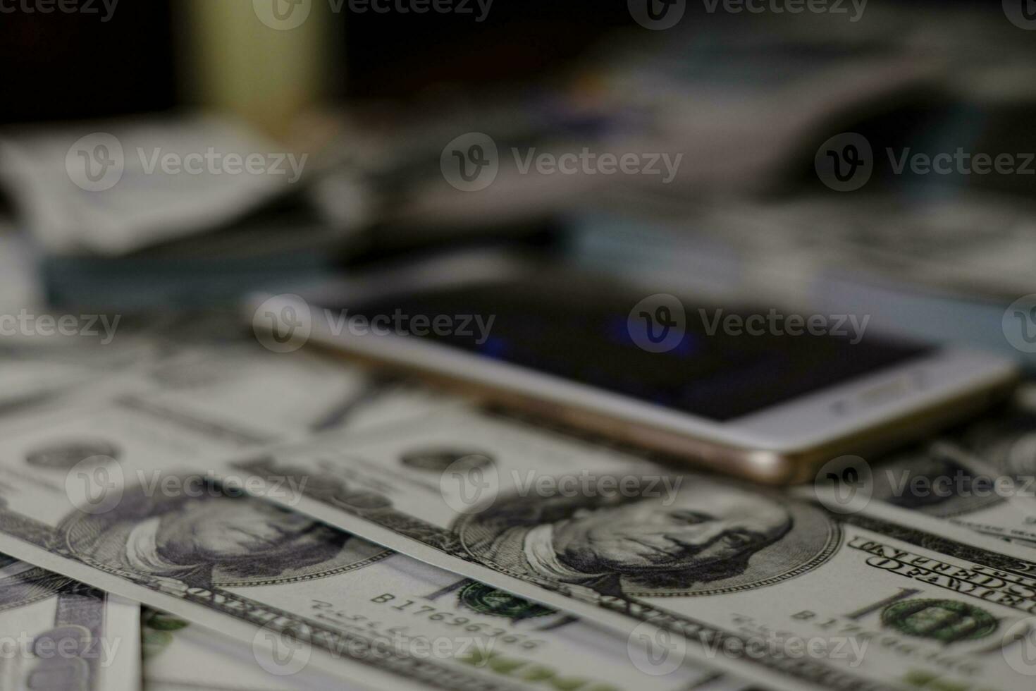 impilare denaro su una pila di banconote da 100 dollari USA con sfondo sfocato foto