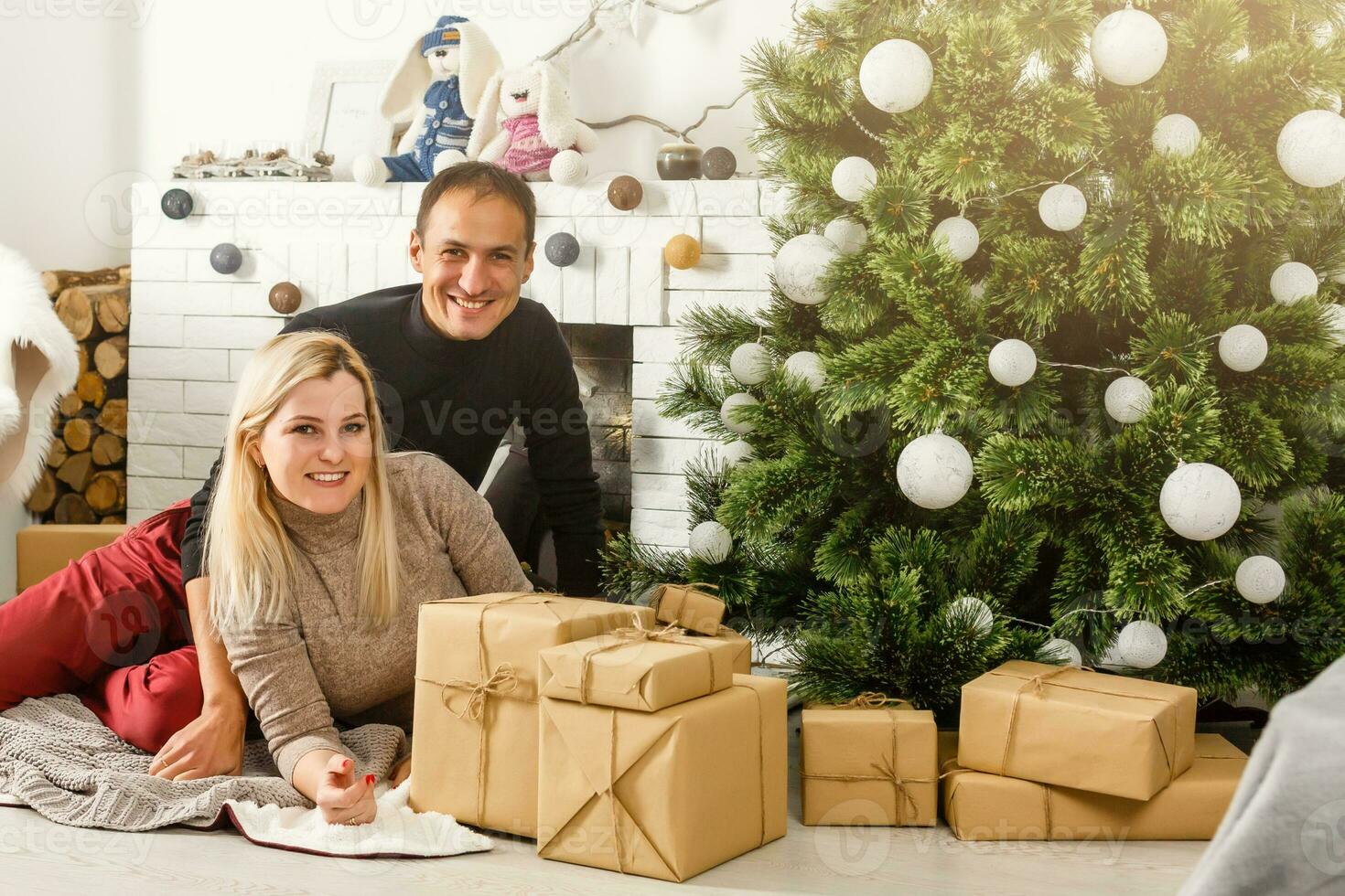 simpatico amore coppia seduta su tappeto nel davanti di il camino. donna e uomo festeggiare Natale foto