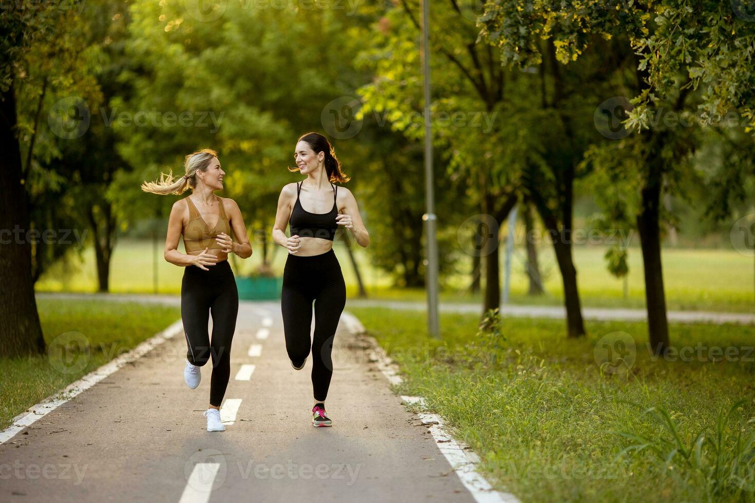 Due bella giovane donne in esecuzione su il corsia nel il parco foto
