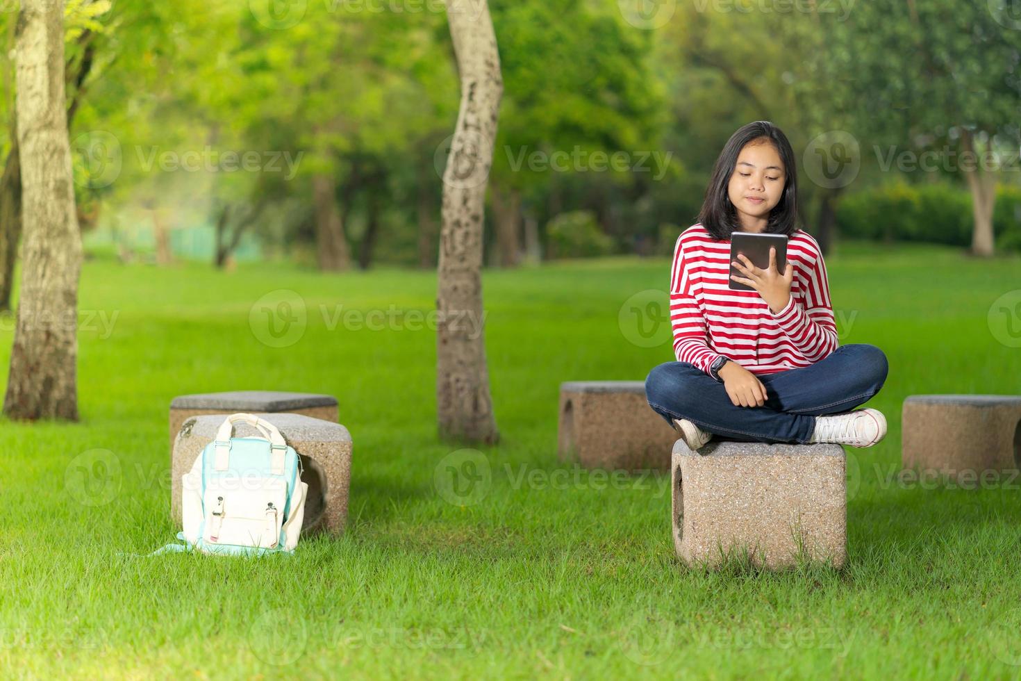 studentessa asiatica che utilizza una tavoletta digitale nel parco della scuola in una soleggiata giornata estiva foto