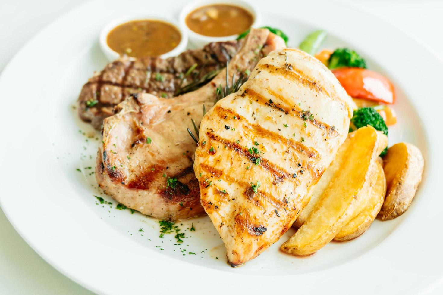 petto di pollo e braciola di maiale con bistecca di manzo e verdure foto