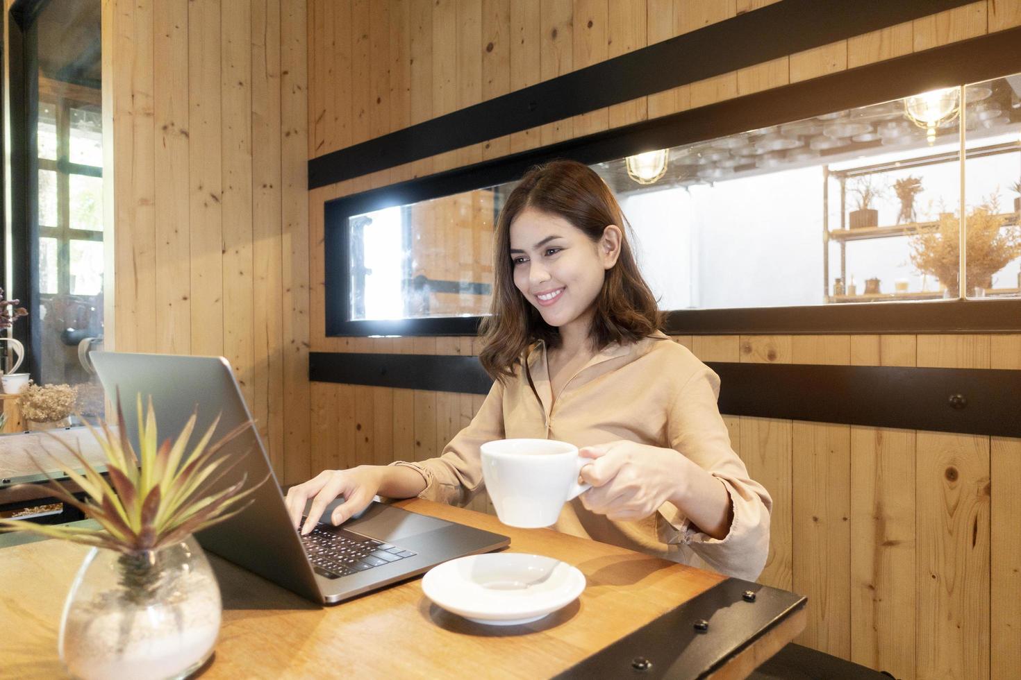 bella donna d'affari sta lavorando con il suo computer portatile in caffetteria foto