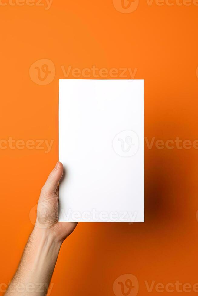 un' umano mano Tenere un' vuoto foglio di bianca carta o carta isolato su arancia sfondo. ai generato foto