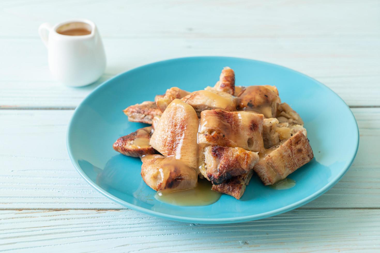 banane grigliate con salsa al caramello al cocco sul piatto foto