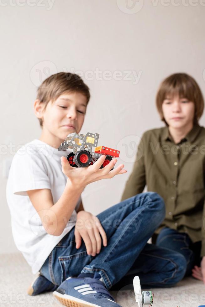 giovani ragazzi che si divertono a costruire auto robot in officina foto