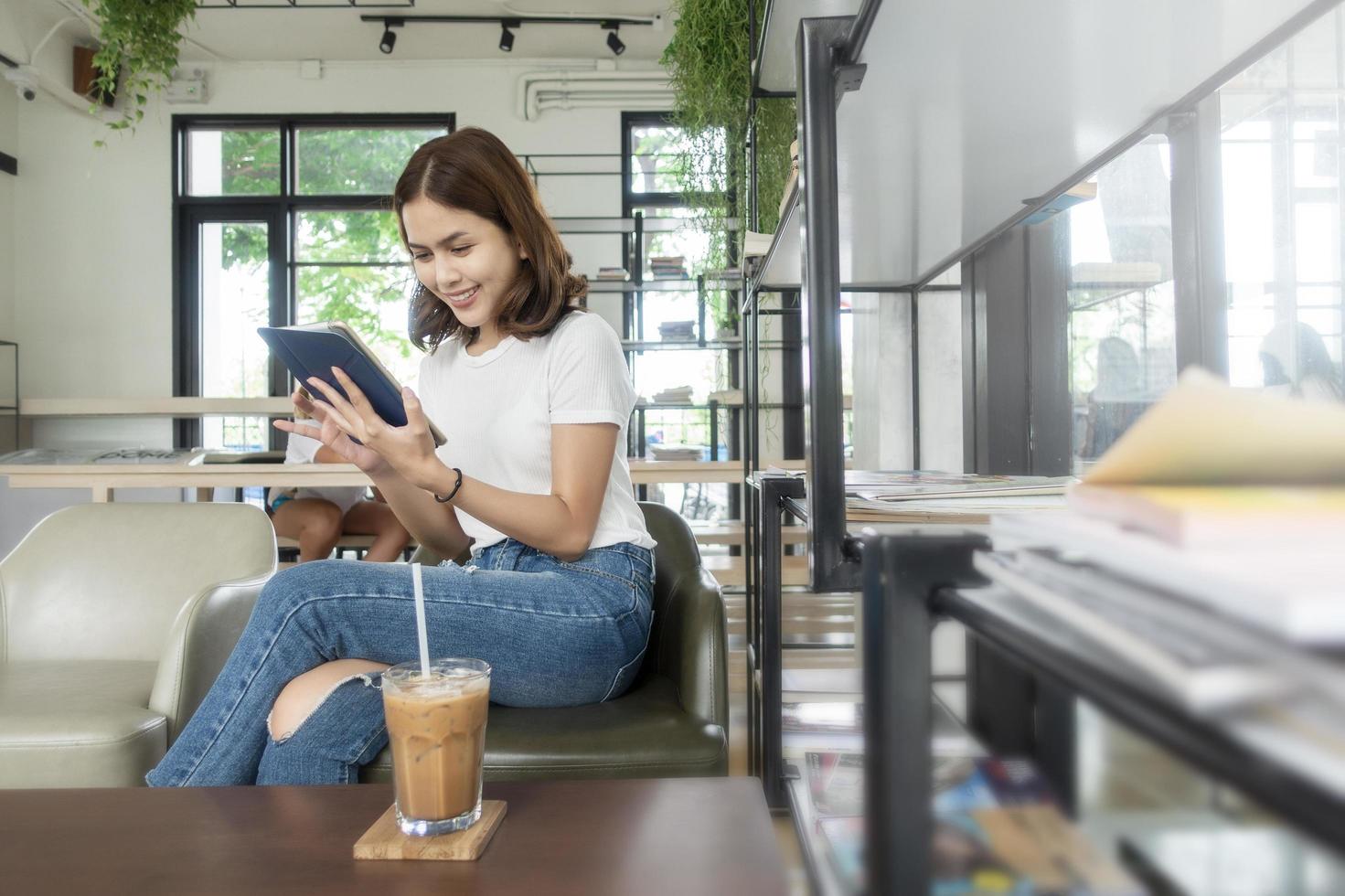 bella ragazza d'affari che lavora con tablet, smartphone e beve caffè nella caffetteria foto