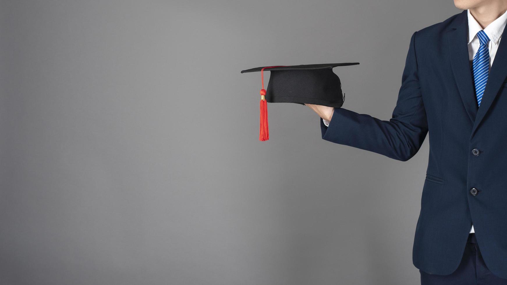 l'uomo d'affari tiene in mano il cappello di laurea, concetto di educazione aziendale foto