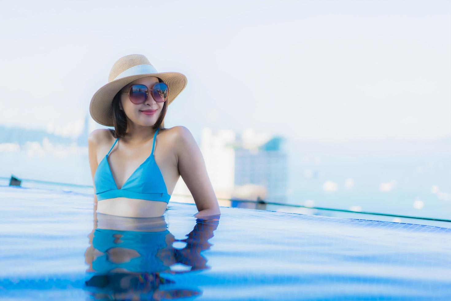 ritratto belle giovani donne asiatiche sorriso felice relax piscina all'aperto nel resort foto