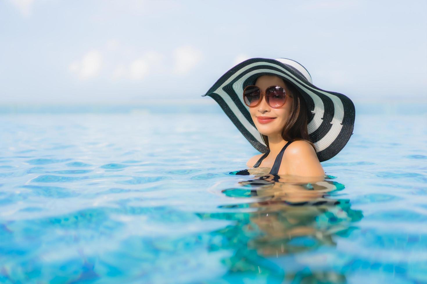 ritratto belle giovani donne asiatiche sorriso felice relax piscina all'aperto nel resort foto