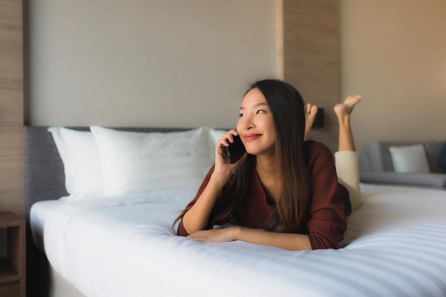 ritratto belle giovani donne asiatiche che utilizzano il telefono cellulare sul letto foto