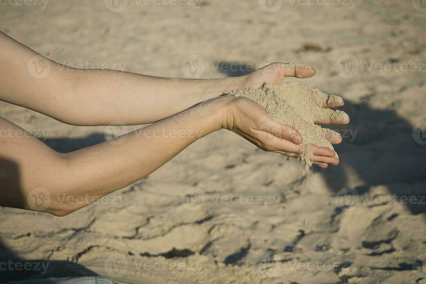 avvicinamento di mani con sabbia caduta su un' spiaggia foto