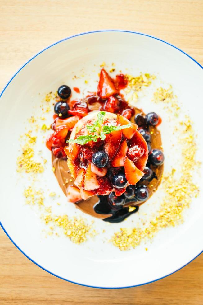 frittelle con frutti di bosco misti nel piatto bianco foto