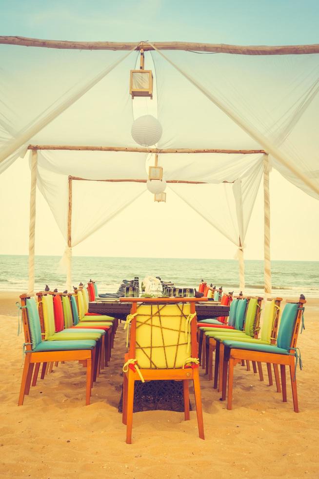 tavolo e sedia apparecchiati in spiaggia per cena foto