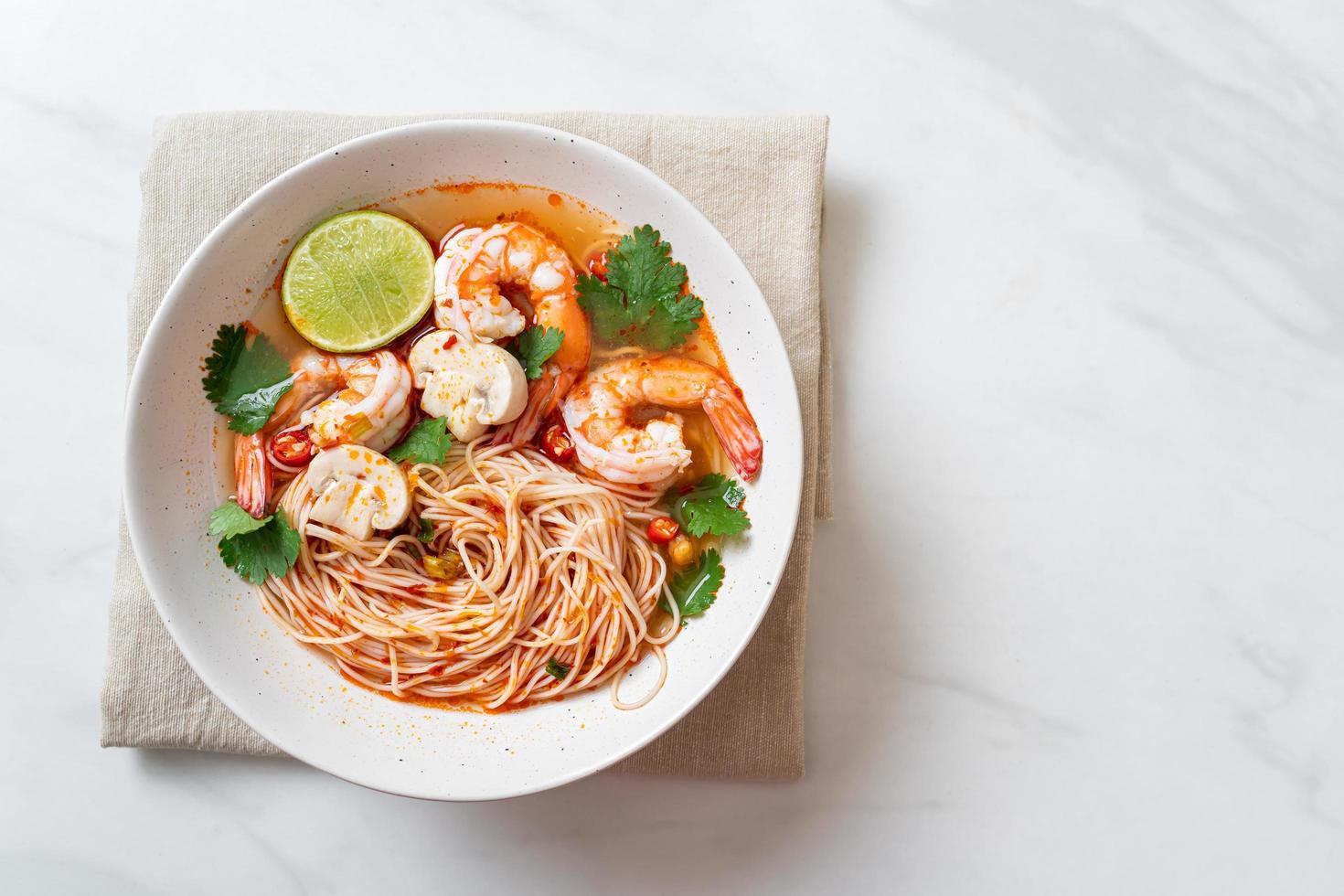 noodles con zuppa piccante e gamberi in una ciotola bianca, o tom yum kung - stile asiatico foto