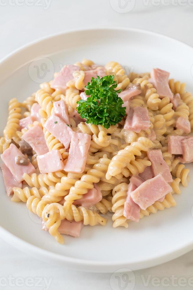 spirali o pasta a spirale salsa di crema di funghi con prosciutto - stile italiano foto