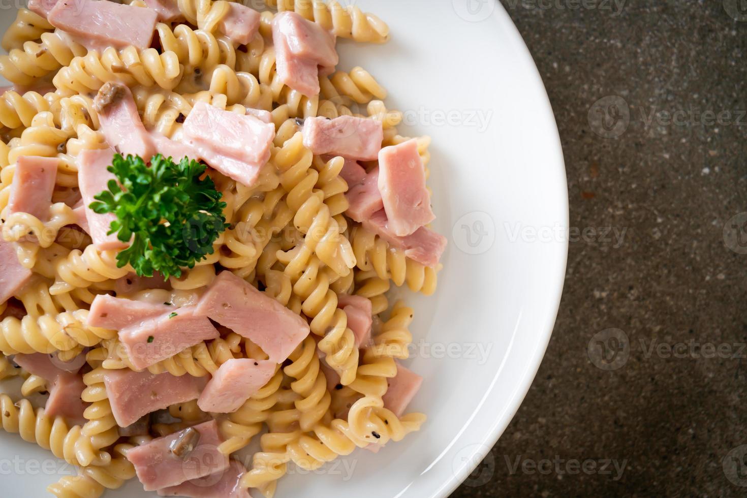 spirali o pasta a spirale salsa di crema di funghi con prosciutto - stile italiano foto