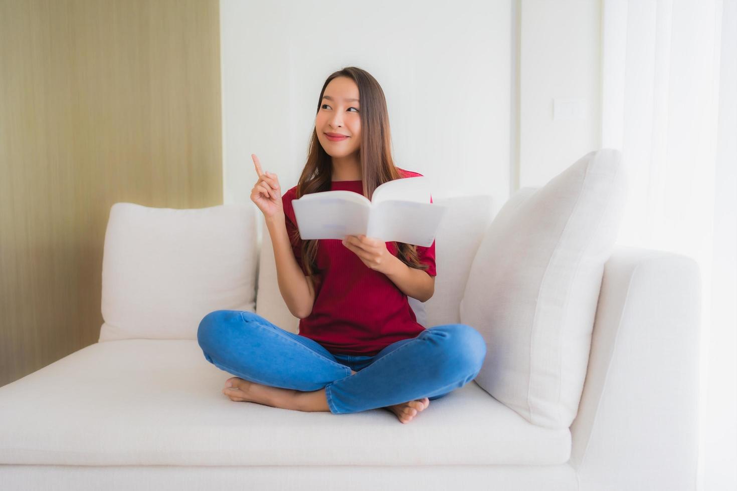 ritratto belle giovani donne asiatiche leggere il libro sulla poltrona del divano foto