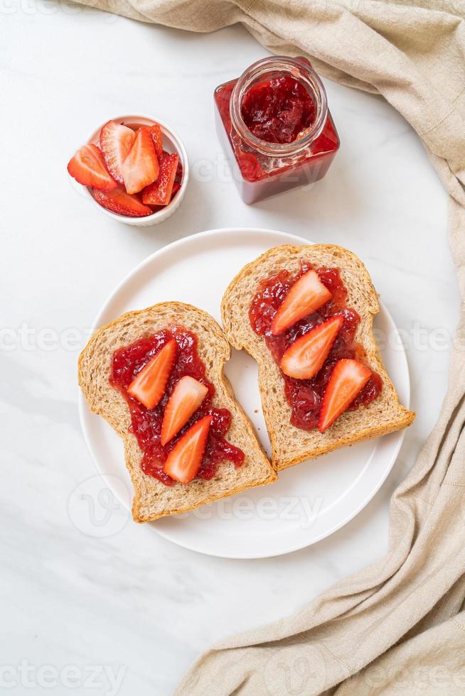 pane integrale fatto in casa con marmellata di fragole e fragole fresche foto