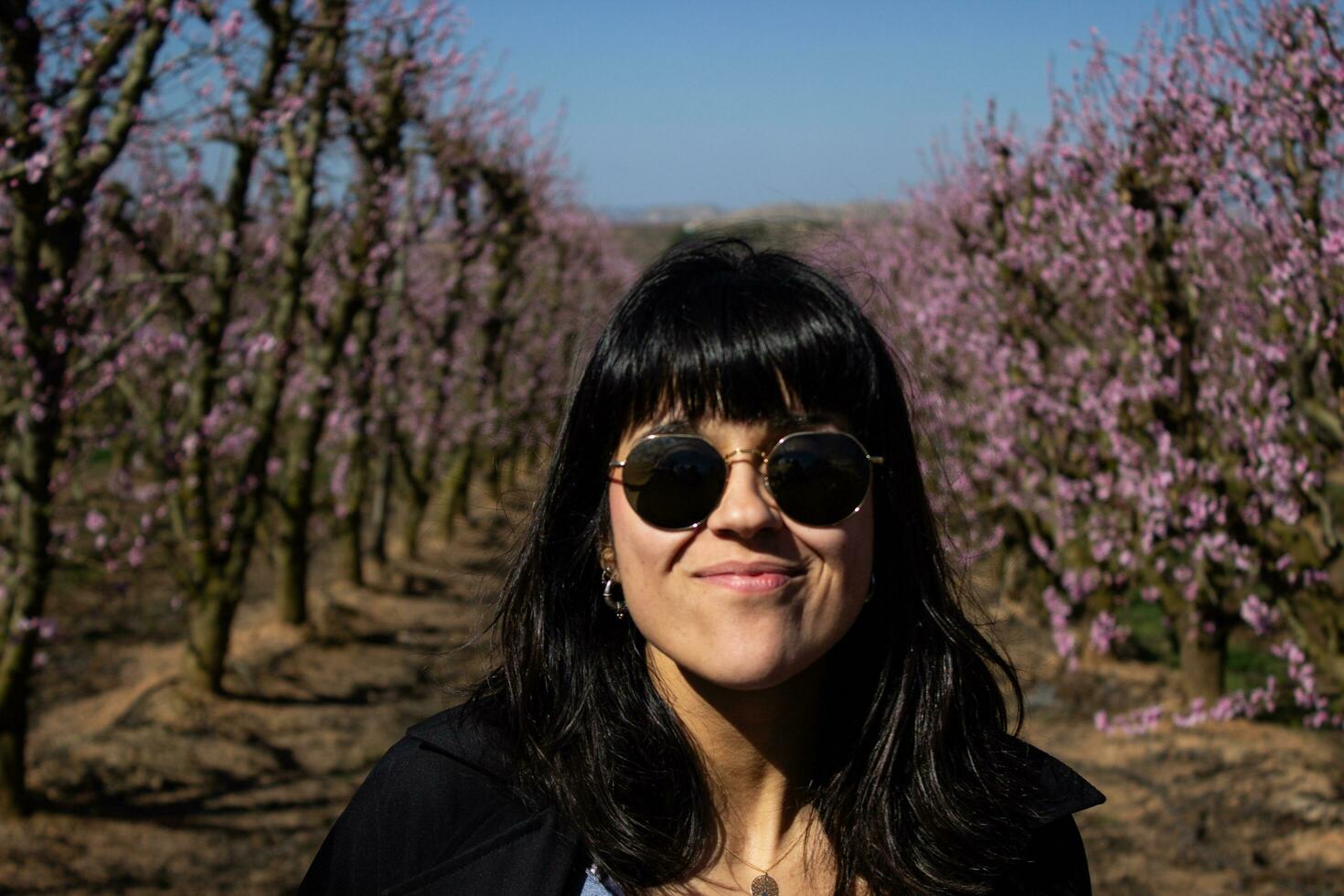 donna tra il bella rosa pesca albero fiori. foto