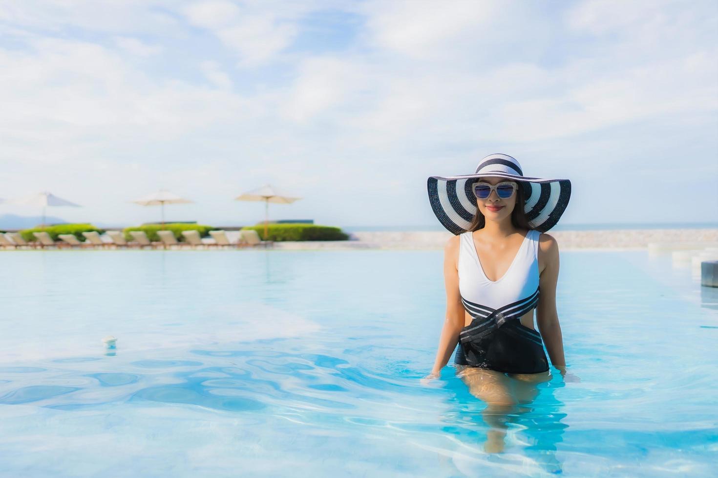 ritratto belle giovani donne asiatiche sorriso felice rilassarsi intorno alla piscina foto