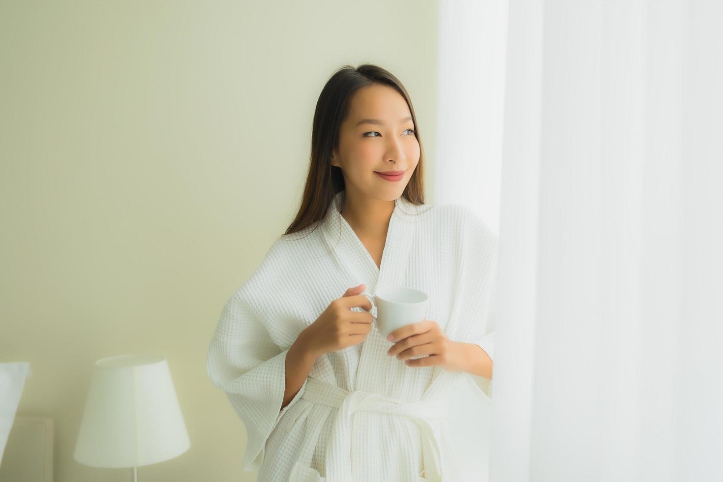 ritratto belle giovani donne asiatiche con tazza di caffè in camera da letto foto