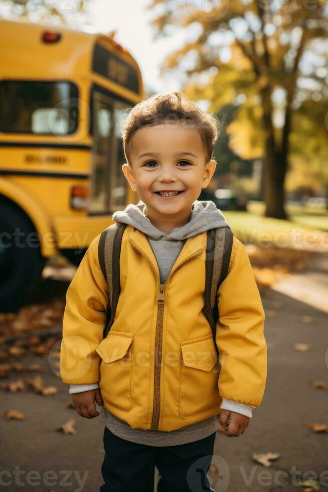 un' giovane bambino avidamente sta nel davanti di un' scuola autobus pronto per imbarcarsi su un' nuovo avventura pieno con apprendimento e amicizie foto