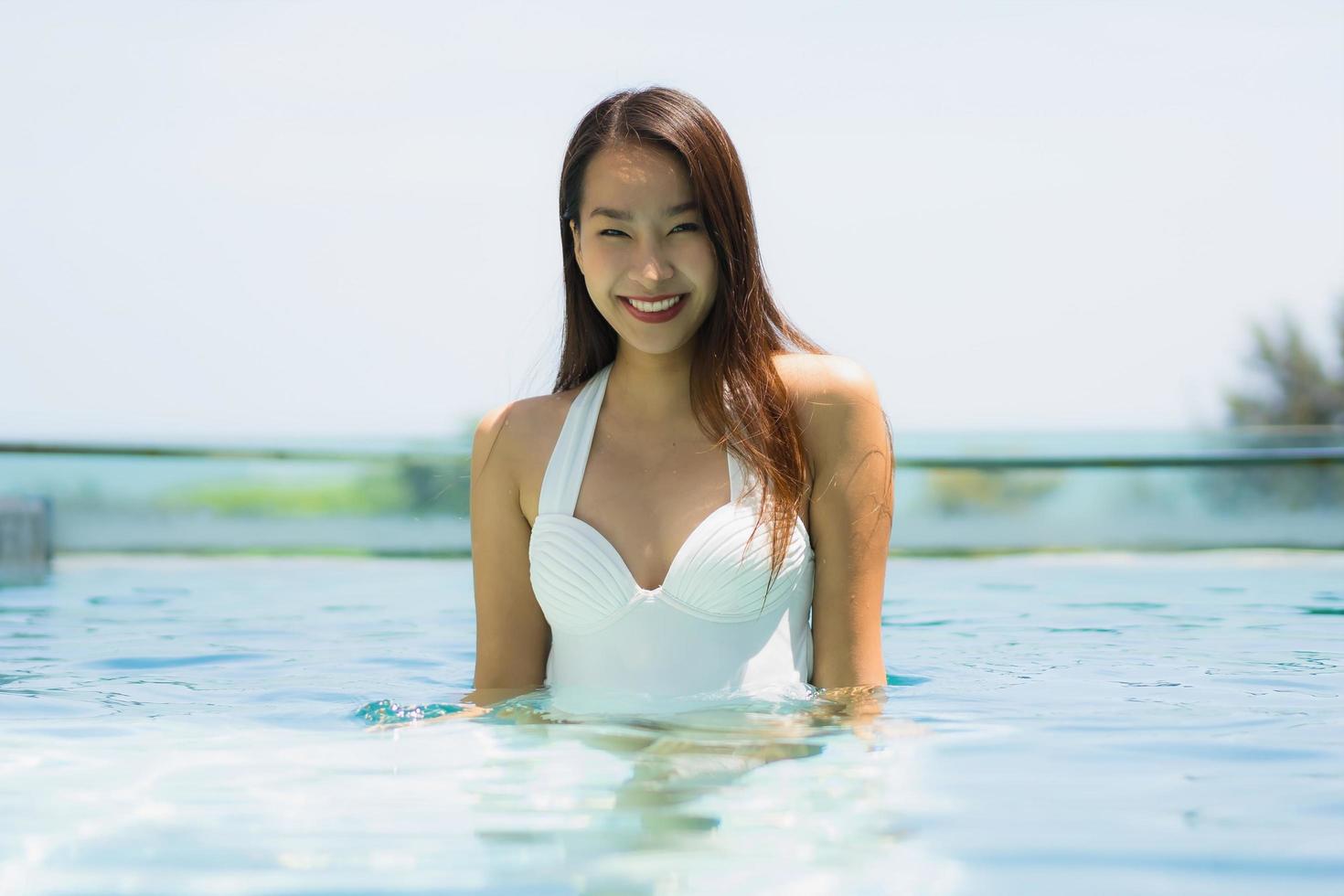 bella giovane donna asiatica felice e sorridente in piscina per rilassarsi viaggi e vacanze foto