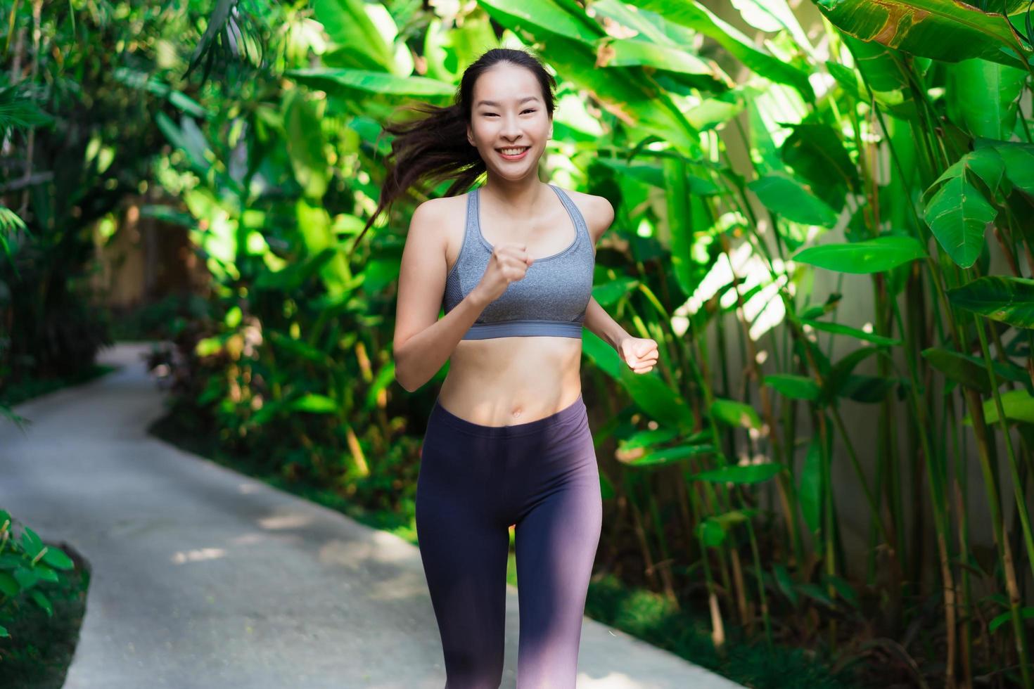 ritratto bella giovane donna asiatica che corre felice e sorridente in giardino foto