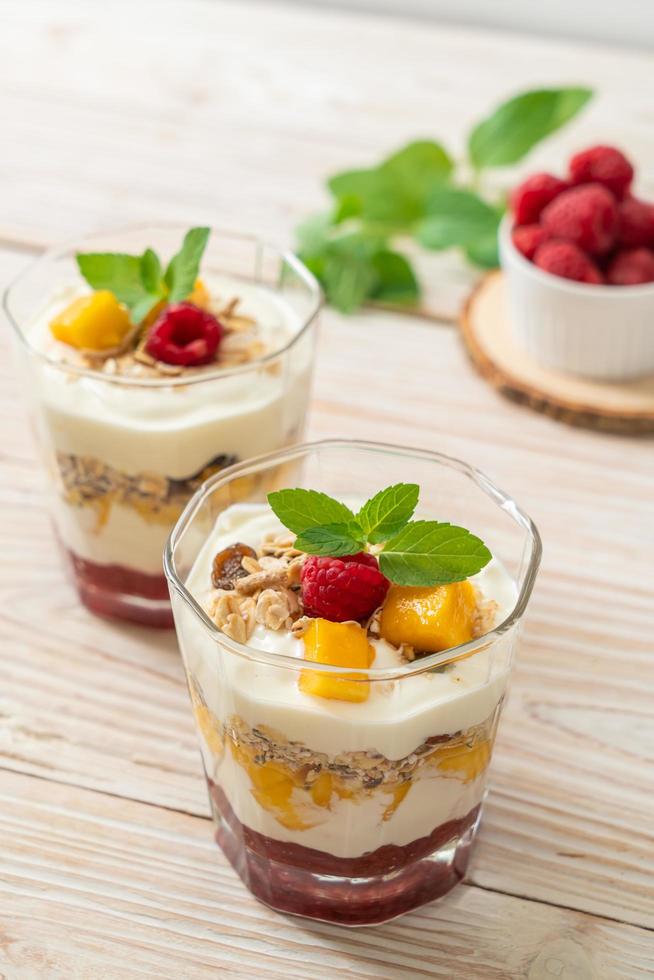 mango fresco fatto in casa e lampone fresco con yogurt e muesli - stile di cibo sano foto