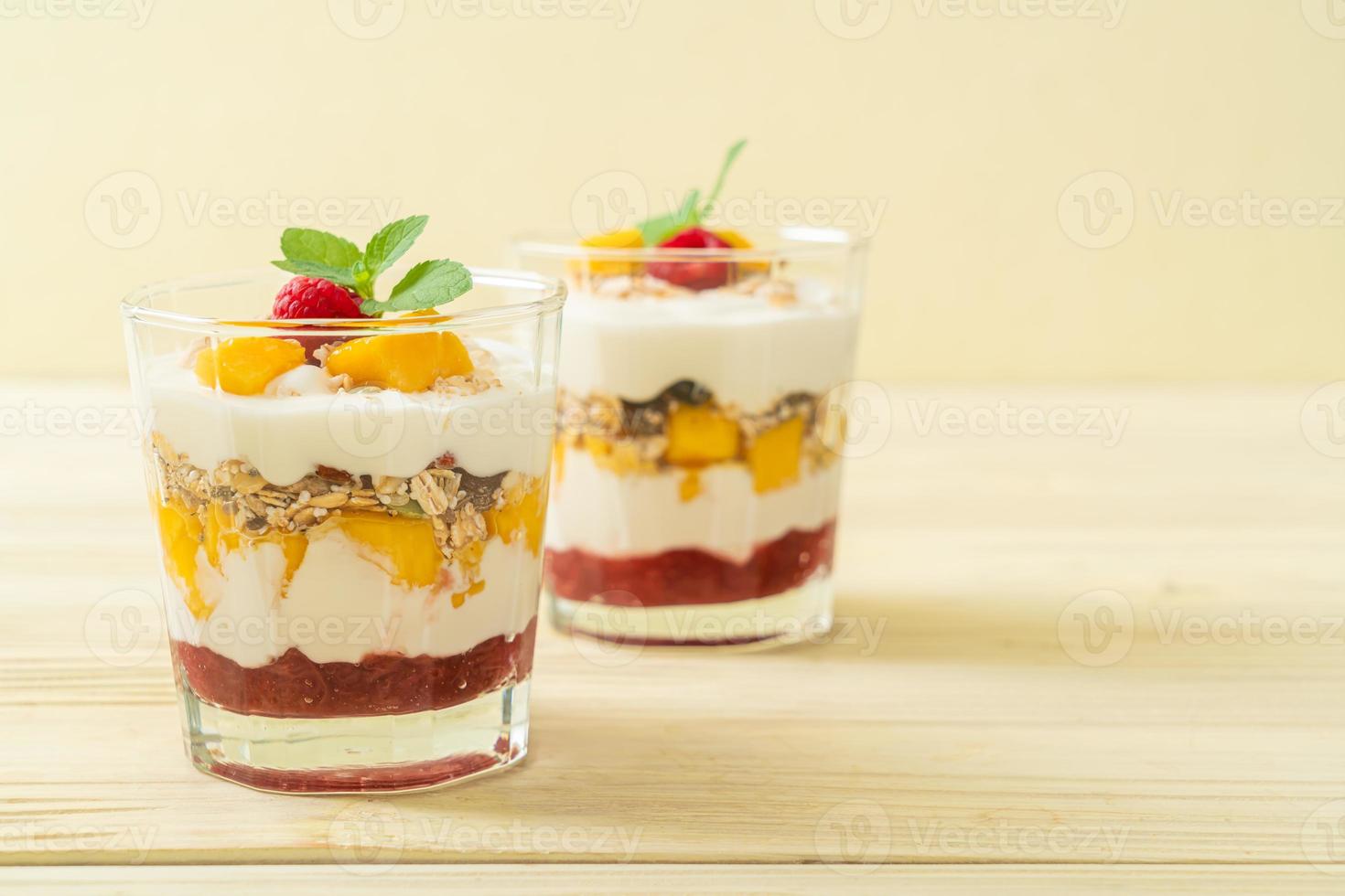 mango fresco fatto in casa e lampone fresco con yogurt e muesli - stile di cibo sano foto