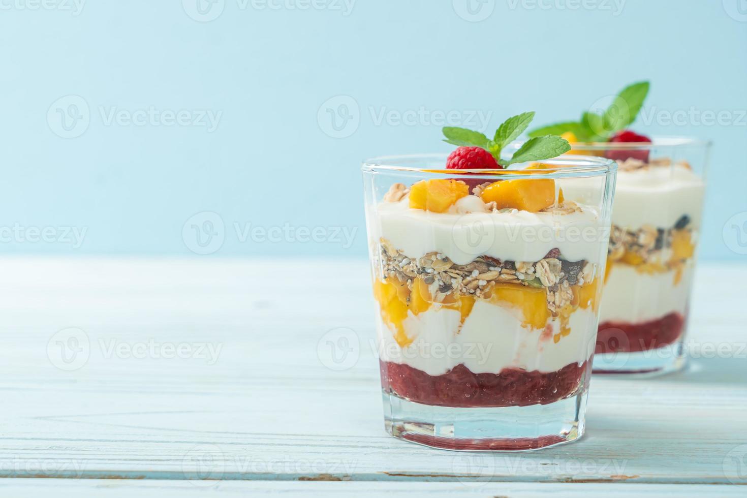 mango fresco fatto in casa e lampone fresco con yogurt e muesli - stile di cibo sano foto