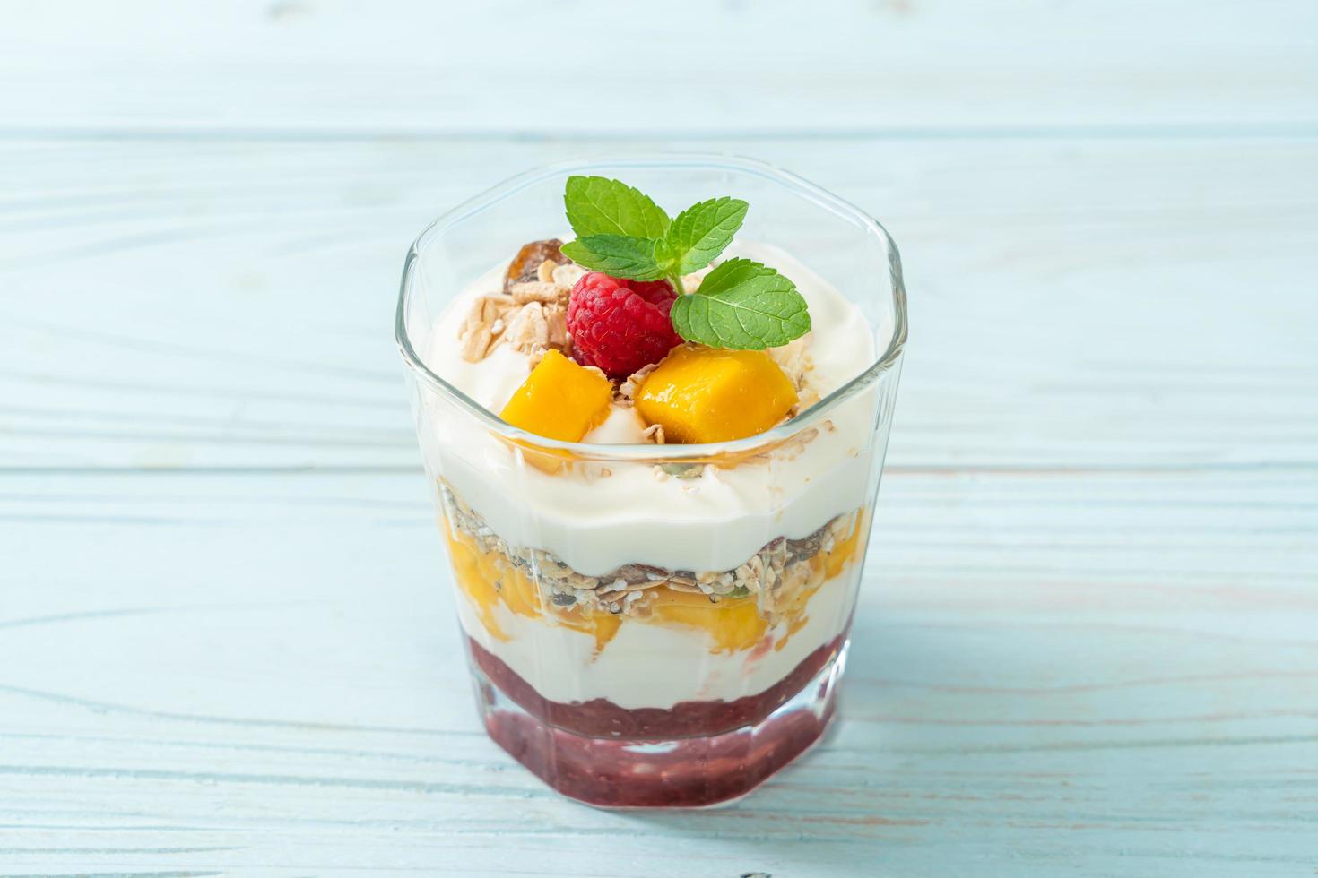 mango fresco fatto in casa e lampone fresco con yogurt e muesli - stile di cibo sano foto