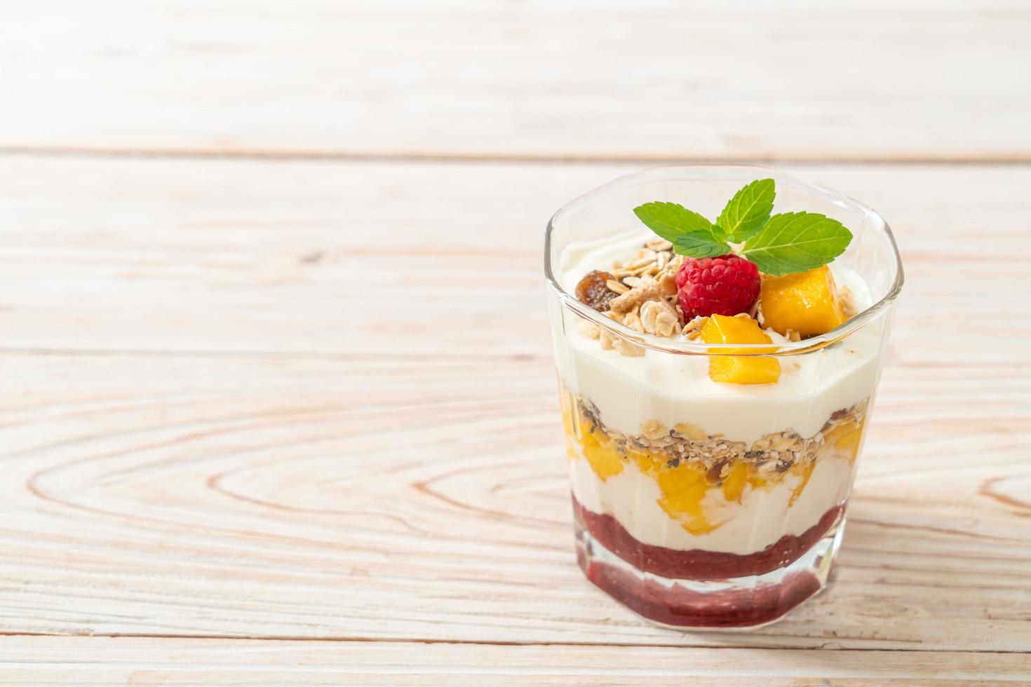 mango fresco fatto in casa e lampone fresco con yogurt e muesli - stile di cibo sano foto