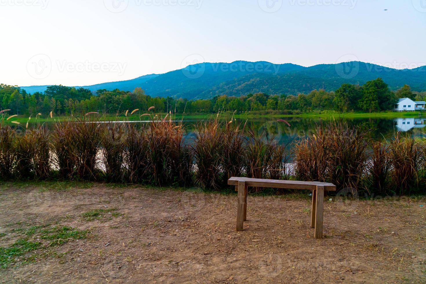 panca di legno con un bellissimo lago a chiang mai con montagne boscose e cielo al crepuscolo in thailandia foto