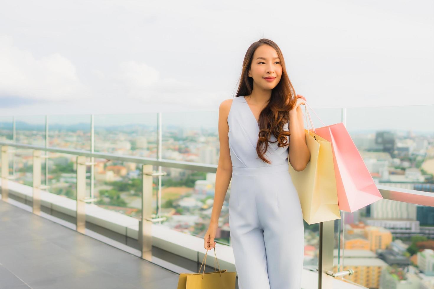 ritratto bella giovane donna asiatica felice e sorridere con la borsa della spesa dal grande magazzino foto