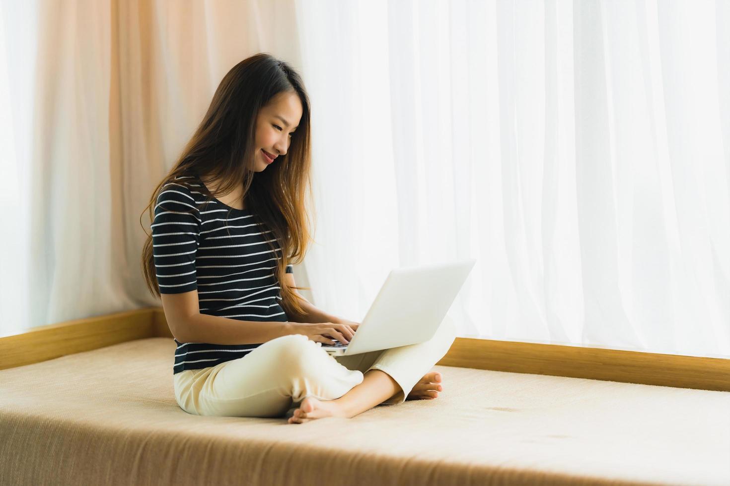 ritratto bella giovane donna asiatica che utilizza computer notebook o laptop sul divano in soggiorno foto