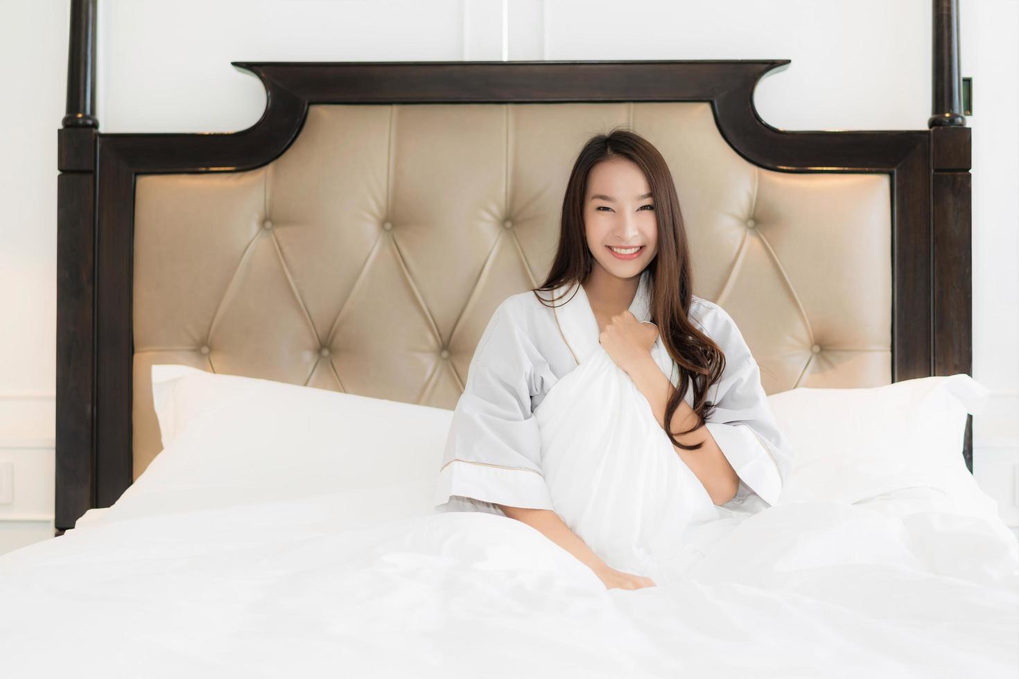 ritratto bella giovane donna asiatica sveglia con felice e sorriso sul letto nell'interno della camera da letto foto