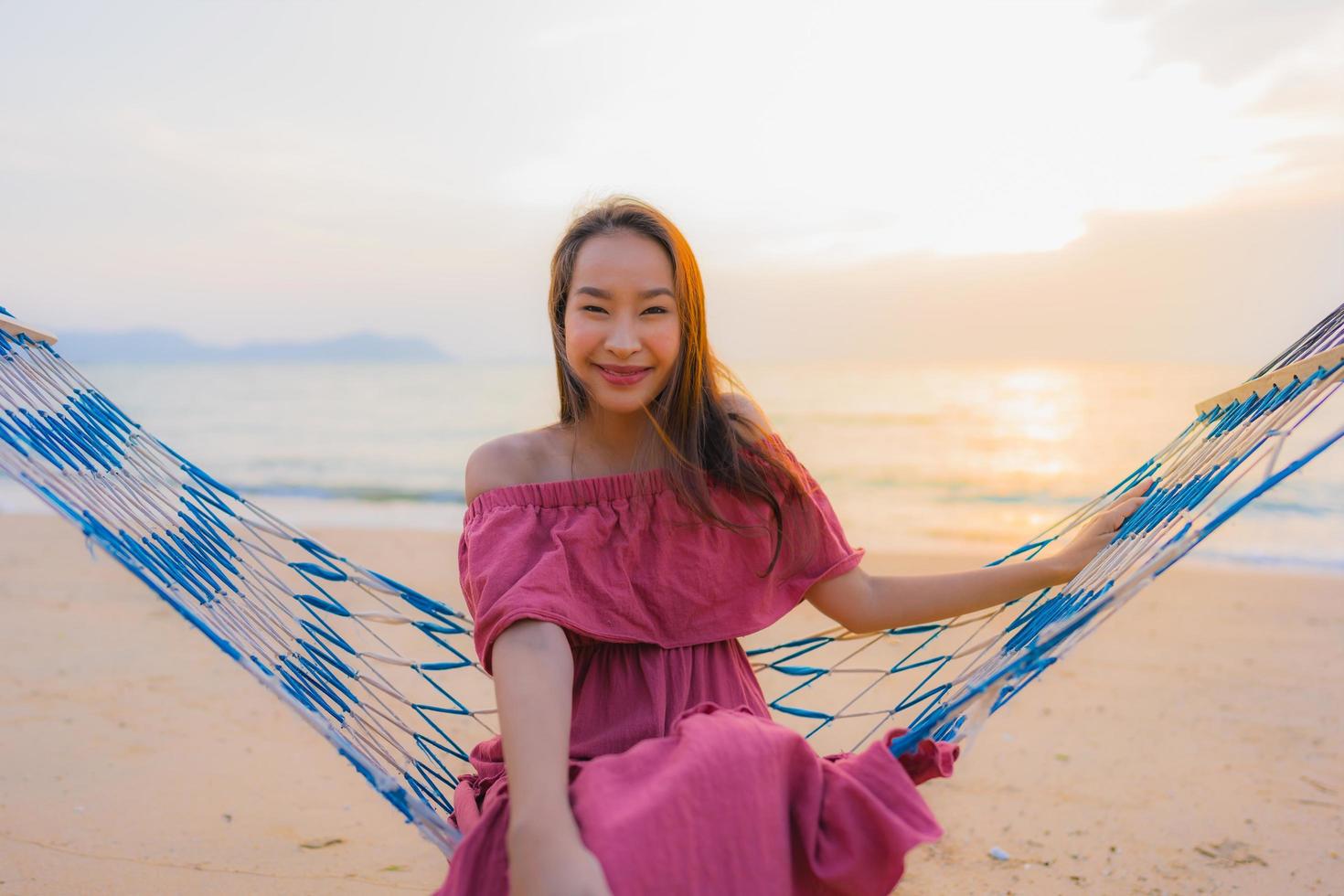 ritratto bella giovane donna asiatica seduta sull'amaca con sorriso felice spiaggia vicina mare e oceano foto