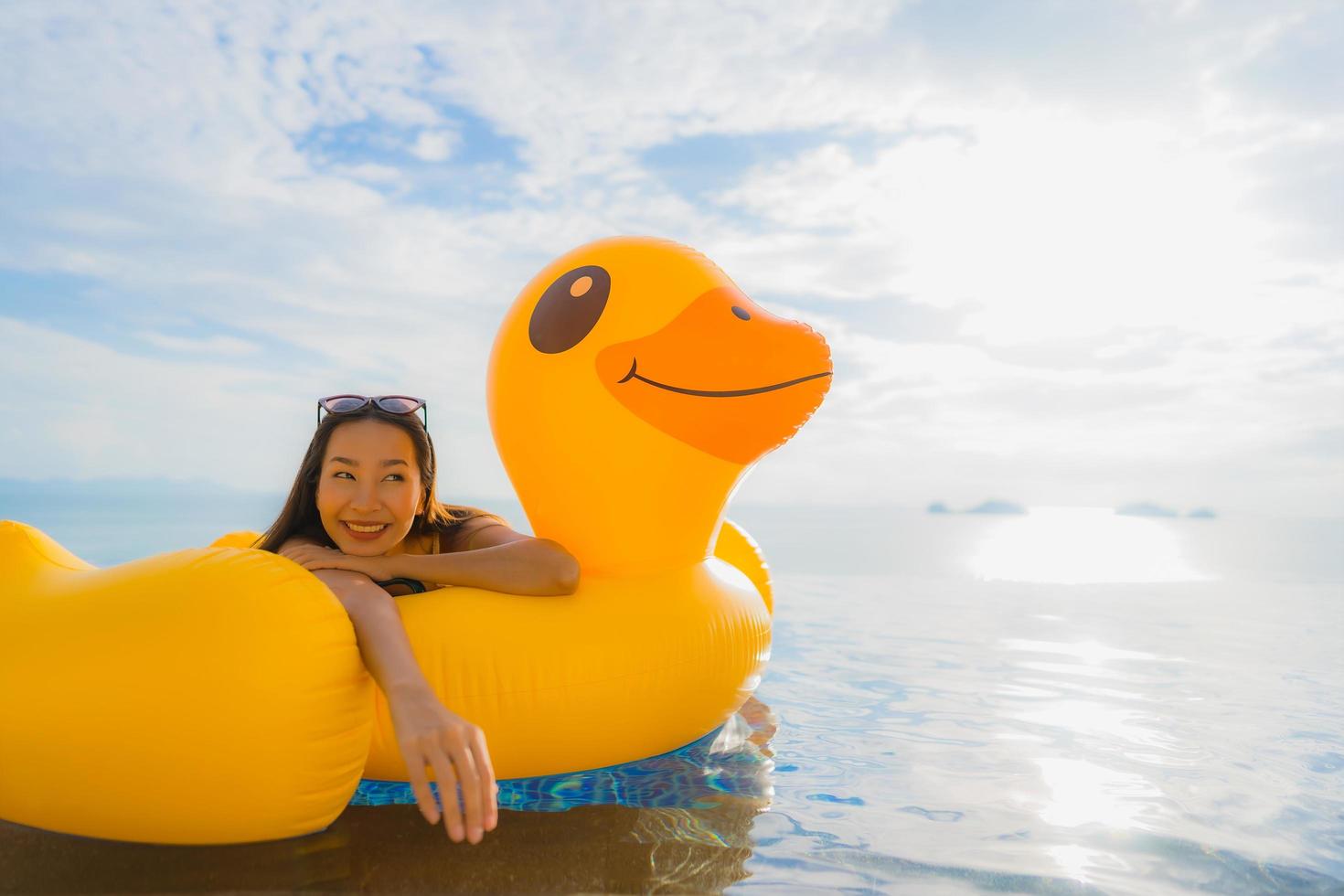 Ritratto di giovane donna asiatica su galleggiante gonfiabile anatra gialla intorno alla piscina all'aperto in hotel e resort foto