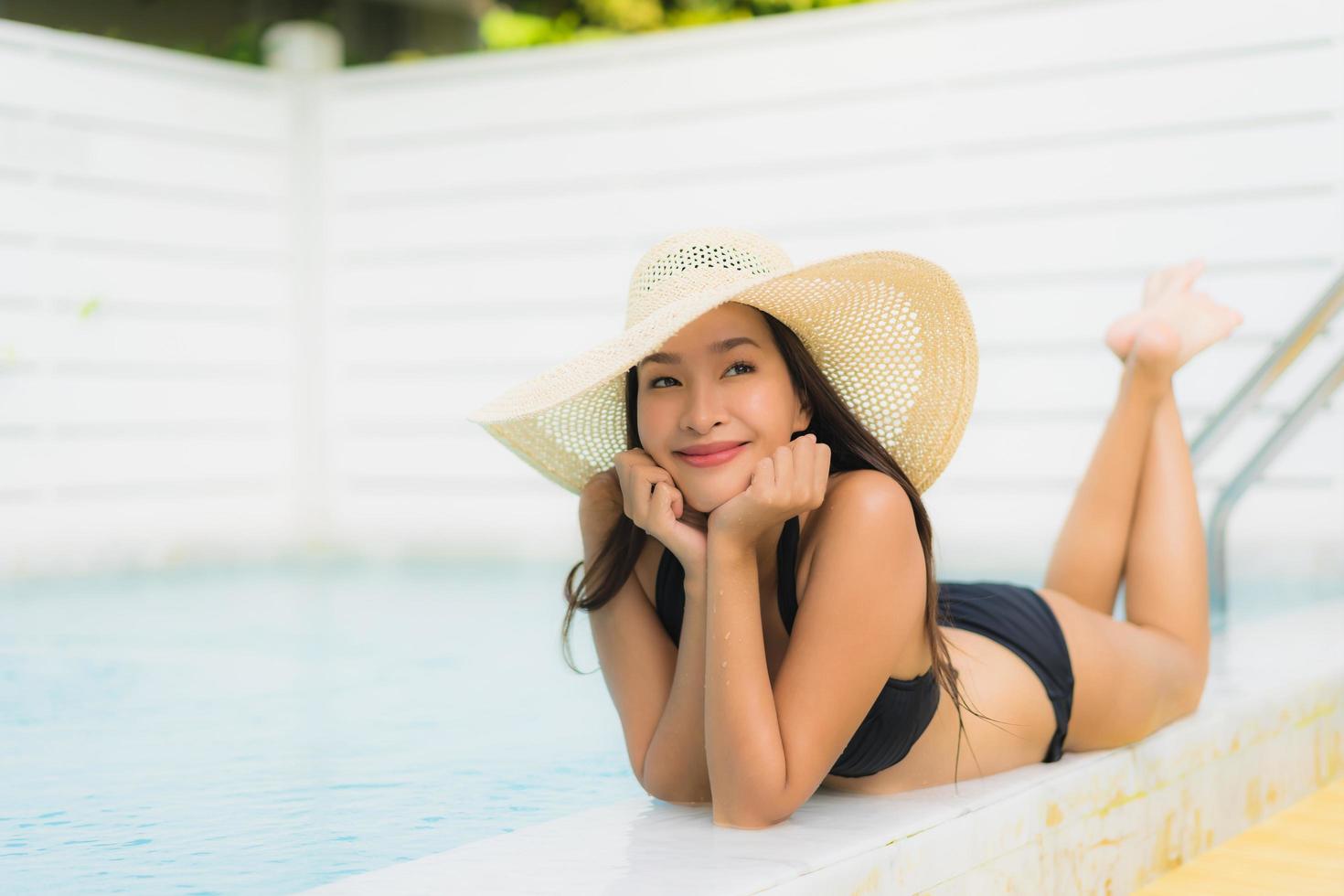 ritratto bella giovane donna asiatica sorriso felice rilassarsi intorno alla piscina all'aperto foto