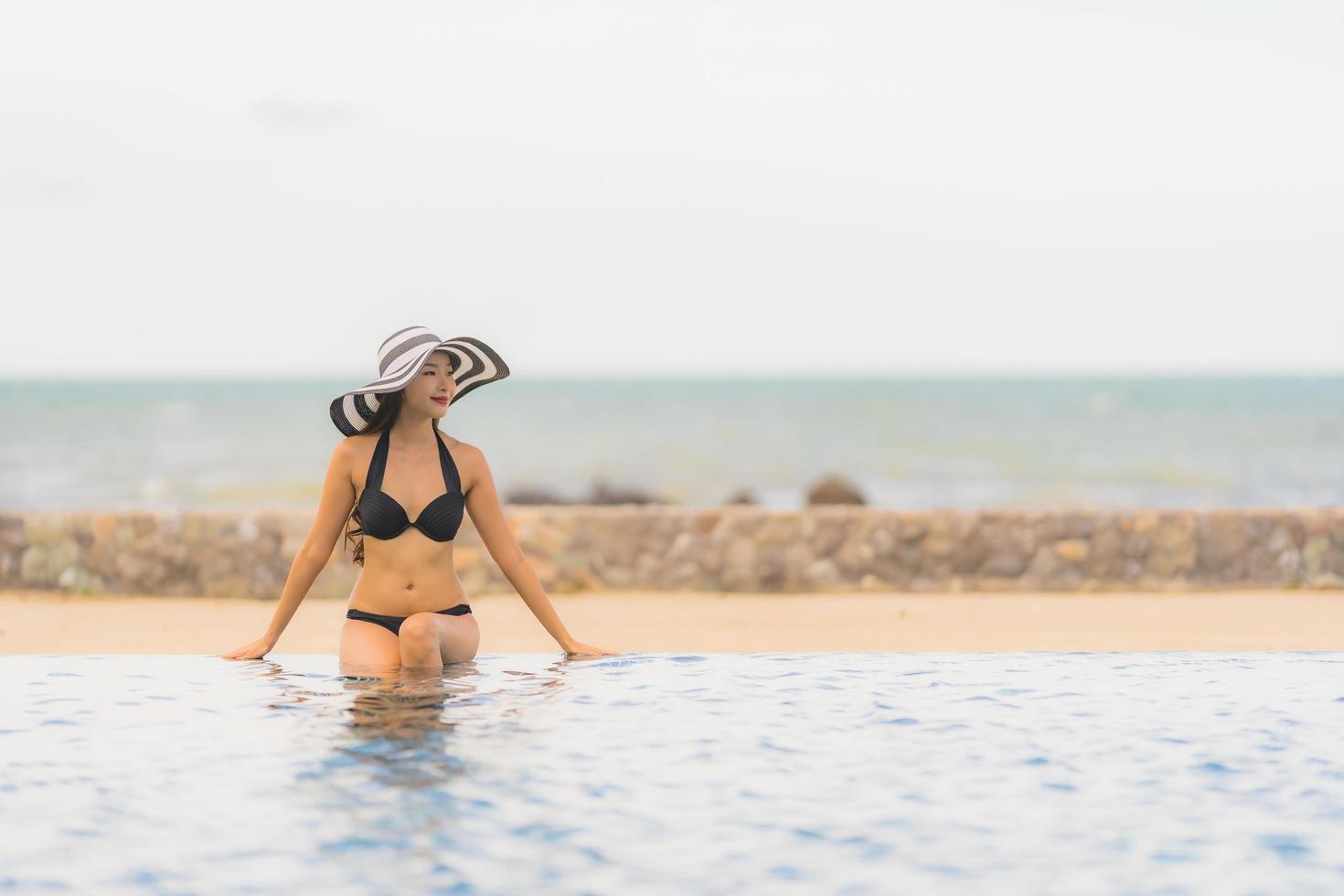 ritratto bella giovane donna asiatica indossare bikini intorno alla piscina in hotel resort quasi mare oceano spiaggia foto