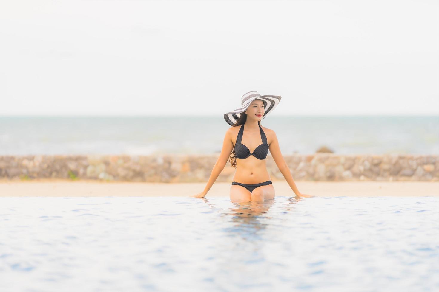 ritratto bella giovane donna asiatica indossare bikini intorno alla piscina in hotel resort quasi mare oceano spiaggia foto