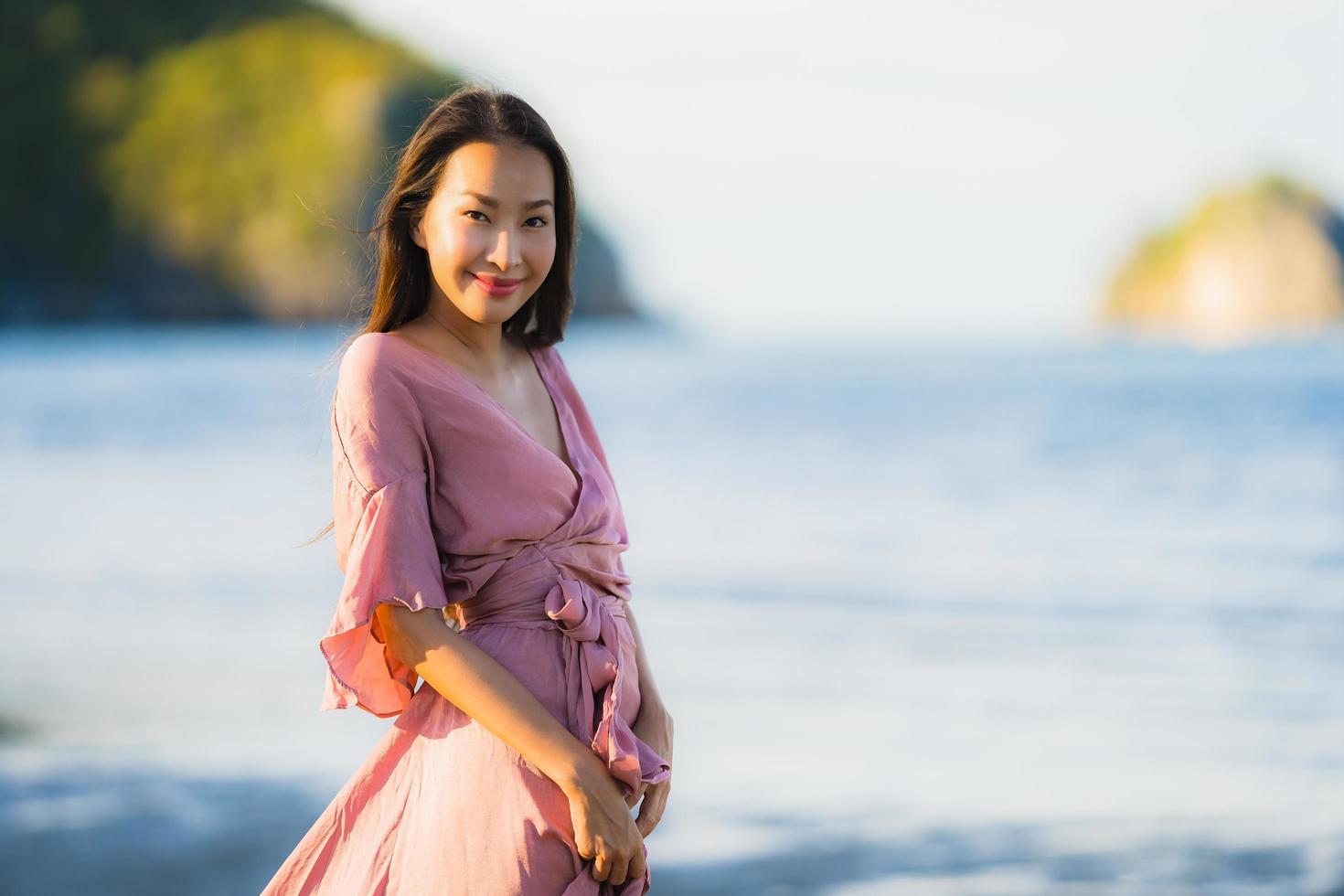 ritratto giovane bella donna asiatica cammina sorriso e felice sulla spiaggia mare e oceano foto