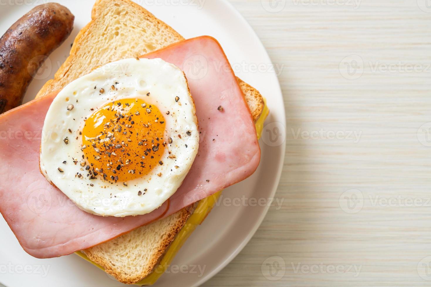 pane fatto in casa formaggio tostato condita con prosciutto e uovo fritto con salsiccia di maiale per colazione foto