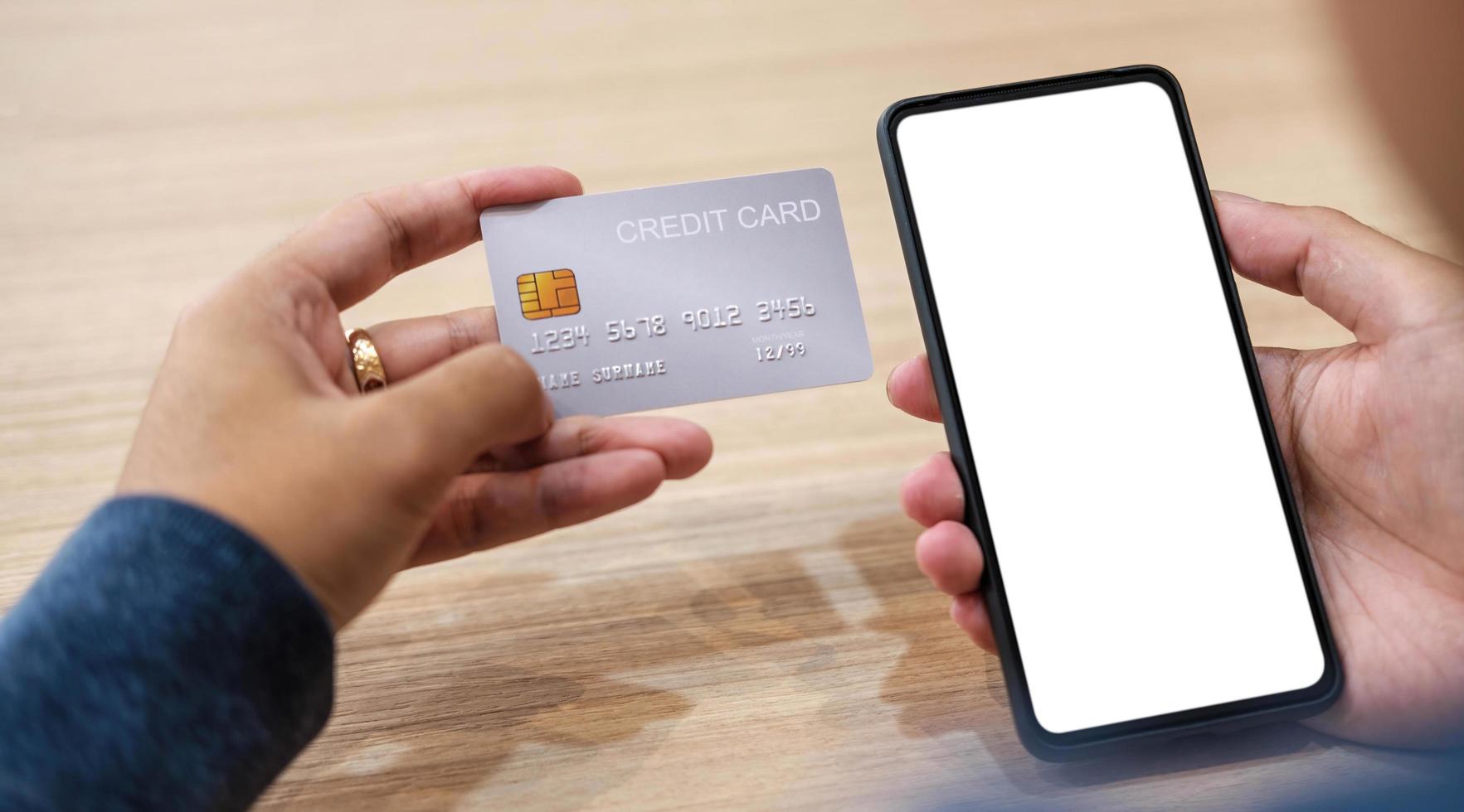 mano ravvicinata della donna che acquista online con carta di credito utilizzando lo smartphone al bar foto