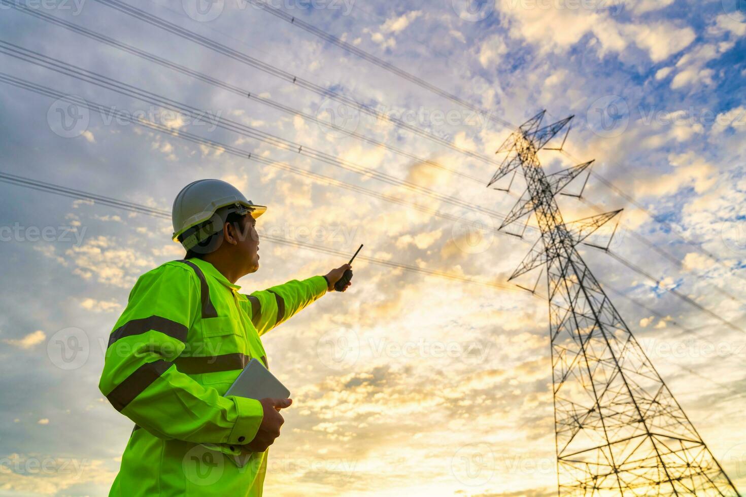 asiatico ingegnere controlli a un' energia stazione per pianificazione opera di generando elettricità a partire dal un' alta tensione trasmissione Torre a tramonto. foto