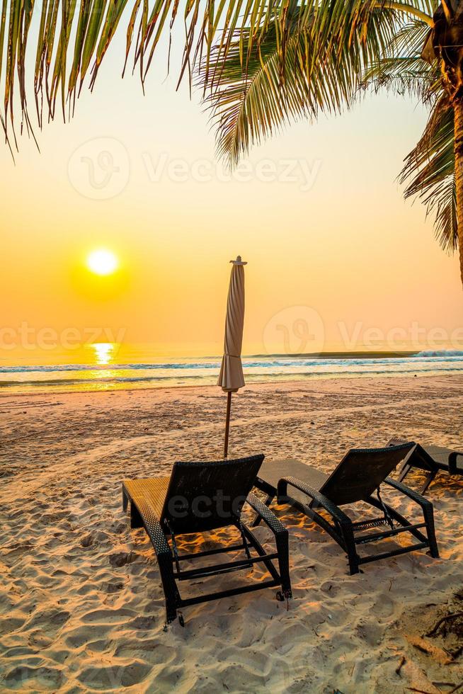 ombrellone sedia da spiaggia con palme e spiaggia del mare all'ora dell'alba - concetto di vacanza e vacanza foto