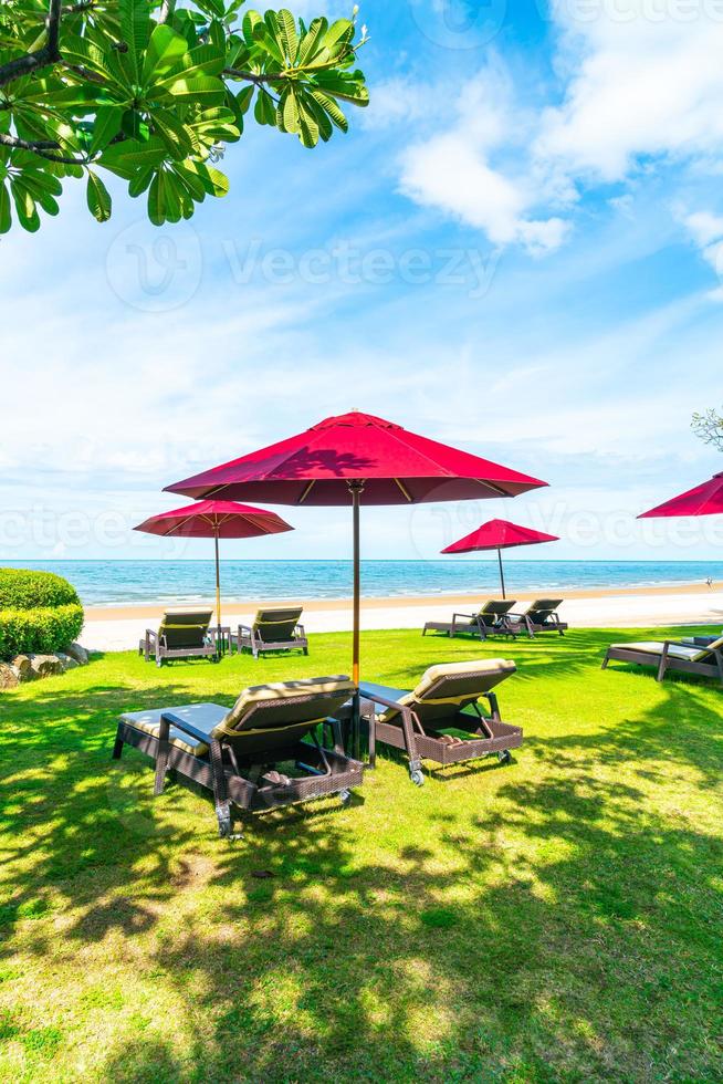 sedie a sdraio e ombrelloni con sfondo spiaggia mare oceano foto