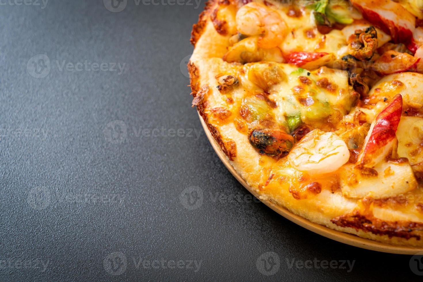 pizza di mare di gamberi, polpo, cozze e granchio su vassoio di legno foto